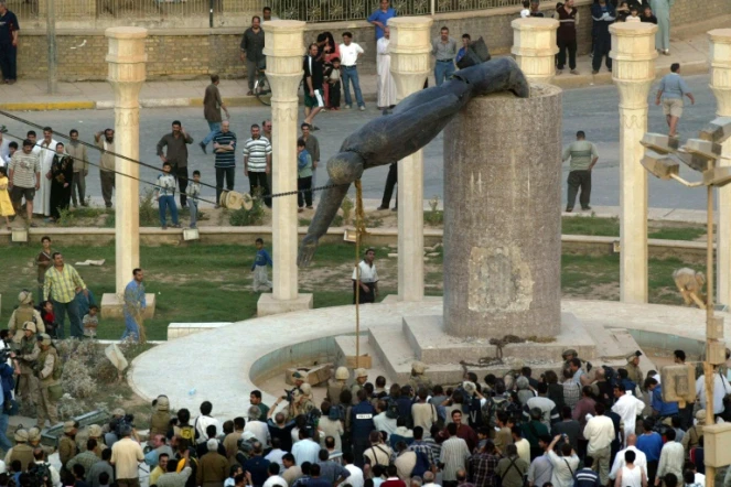 Les Irakiens regardent le déboulonnement à Bagdad de la statue du président Saddam Hussein, après son renversement consécutif à l'invasion américaine de l'Irak, le 9 avril 2003