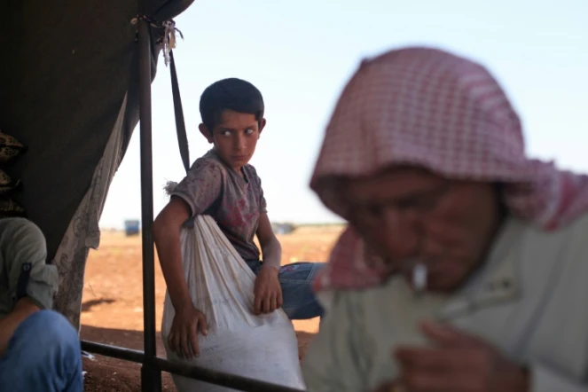 Un homme âgé et un enfant syrien dans une tente où ils se sont installés, à proximité d'un poste d'observation de soldats turcs dans la province d'Idleb en Syrie, dans l'espoir d'être protégés en cas d'assaut du régime syrien. Photo prise le 5 septembre 2018 près de Sarmane