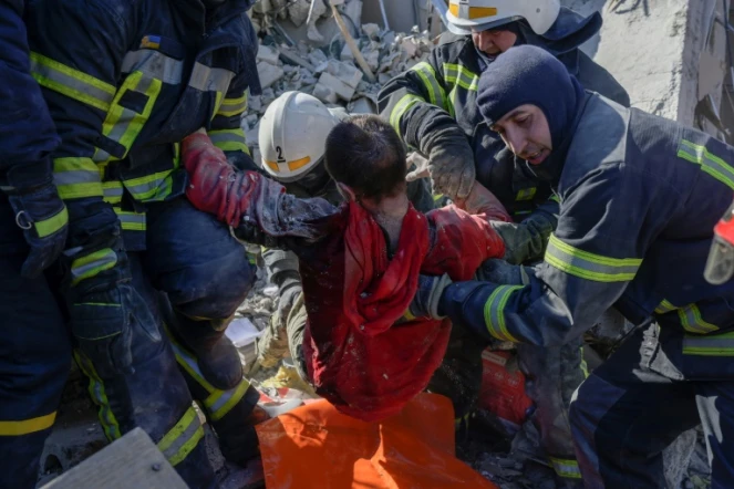 Des sauveteurs évacuent un soldat ukrainien sauvé après avoir été coincé 30 heures dans les débris d'une caserne militaire touchée par des roquettes russes, à Mykolaïv, dans le sud de l'Ukraine, le 19 mars 2022

