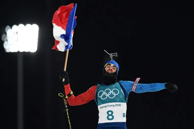 Martin Fourcade brandit le drapeau tricolore de la victoire sur la ligne d'arrivée de la poursuite 12,5 km de Pyeongchang, le 12 février 2018