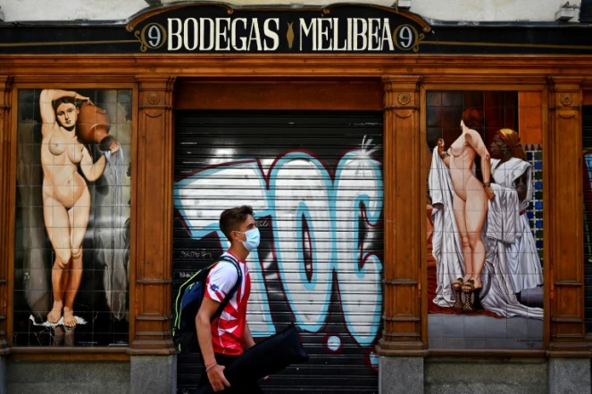 Un jeune homme passe devant un bar fermé à Madrid, en Espagne, le 9 juillet 2020