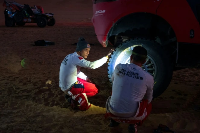 Sebastien Loeb et son co-pilote Fabian Lurquin jettent un oeil à leur Hunter de Prodrive au mitan de l'étape "48h chrono" du Dakar dans le désert de "l'Empty Quarter" en Arabie saoudite le 11 janvier 2024