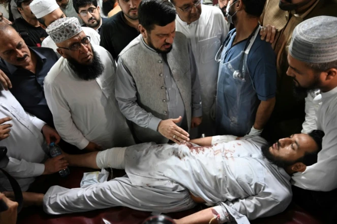 Le gouverneur de la province de Khyber Pakhtunkhwa, Haji Ghulam Ali (centre), réconforte un homme blessé lors de l'attentat suicide contre un meeting politique, le 30 juillet 2023 dans un hôpital de Peshawar (Pakistan)
