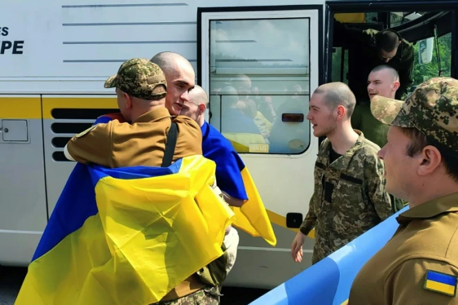 Photo prise et diffusée par le service de presse présidentiel ukrainien, le 9 juin 2025, de prisonniers de guerre ukrainiens enveloppés de drapeaux nationaux après un échange dans un lieu non divulgué