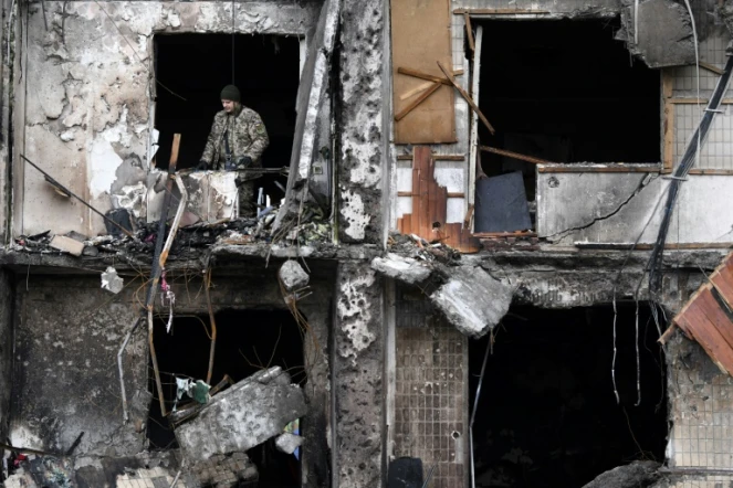 Un soldat ukrainien consate les dégâts dans un immeuble endommagé par des tirs russes à Kiev, le 26 février 2022