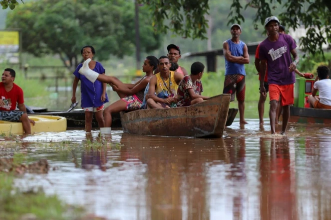 Des habitants utilisent une barque pour traverser un zone inondée dans le quartier Joaia do Atlantico, à Ilheus, dans le sud de l'Etat  brésilien de Bahia