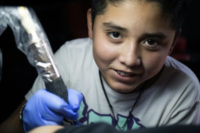 Brandon Burgos, 11 ans, réalise un tatouage sur un client, le 10 novembre 2021 à Puebla, au Mexique