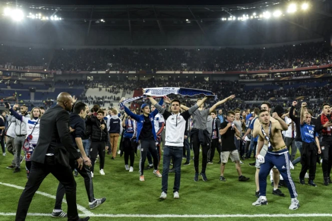Des supporters lyonnais du Virage Sud envahissent la pelouse pour échapper à des jets de projectiles de supporters turcs, le 13 avril 2017 au Parc OL