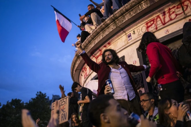 Un homme le poing levé lors d'un rassemblement au soir du second tour des législatives place de la République à Paris, le 7 juillet 2024