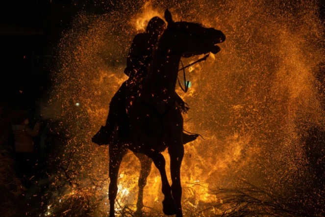 Un cheval et son cavalier traversent un brasier dans le village espagnol de San Bartolome de Pinares pour les traditionnelles "Luminarias", le 16 janvier 2022