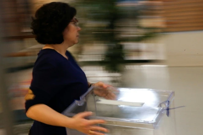 Une femme apporte une urne dans un bureau de vote de L'Hospitalet del Llobregat le 20 décembre 2017 à la veille des élections en Catalogne