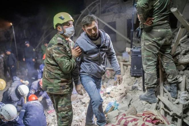 Un secouriste assiste un habitant sur un site touché par un missile à Gandja (Azerbaïdjan) le 17 octobre 2020