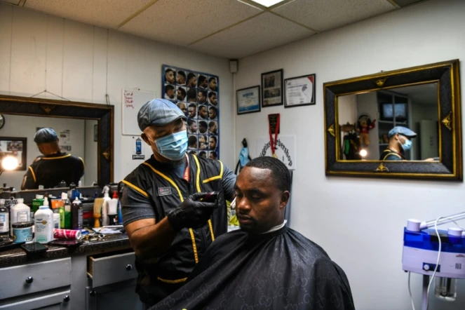 Antonio Wiggins (G) coupe les cheveux de James Bennett dans son salon, à Jackson, le 26 septembre 2020