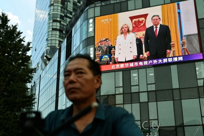 Un homme passe à Pékin devant un écran montrant la rencontre entre la cheffe du gouvernement italien Giorgia Meloni et le président chinois Xi Jinping le 28 juillet 2024