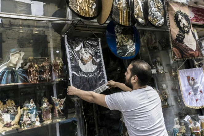 Un vendeur égyptien accroche une image du Christ à l'extérieur de sa boutique d'objets et de bibelots religieux, le 11 avril 2017 dans le quartier de la Choubra, au Caire