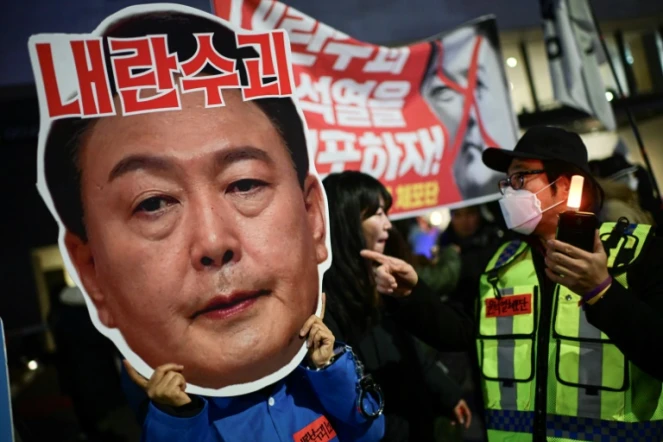 Un manifestant brandit un portrait du président sud-coréen Yoon Suk Yeol, lors d'un rassemblement pour sa démission, le 8 décembre 2024 à Séoul