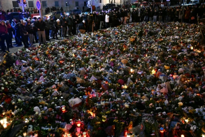 Des personnes se recueillent devant un mémorial composé de fleurs et de bougies en hommage aux victimes d'un attentat à la voiture bélier sur un marché de Noël, à Magdebourg, le 23 décembre 2024 en Allemagne