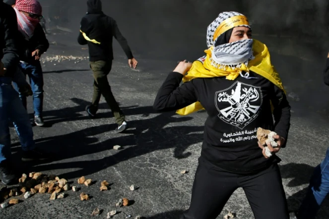 Une Palestinienne jette des pierres aux soldats israéliens à Ramallah, le 11 décembre 2017, pour protester contre la décision américaine de reconnaître Jérusalem comme capitale d'Israël