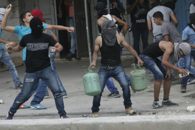De jeunes palestiniens lancent des pierres contre les forces de sécurité israéliennes au checkpoint de Qalandia entre Jérusalem et Ramallah, le 6 octobre 2015