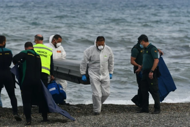 Des employés des pompes funèbres portent le corps d'un migrant sur la plage de l'enclave espagnole de Ceuta, le 20 mai 2021
