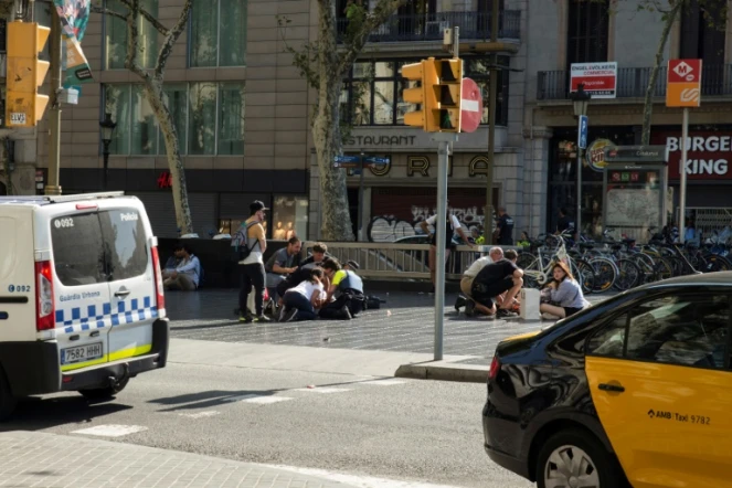 Des personnes viennent en aide à des victimes blessées dans l'attentat à la camionnette sur les Ramblas à Barcelone, le 17 août 2017