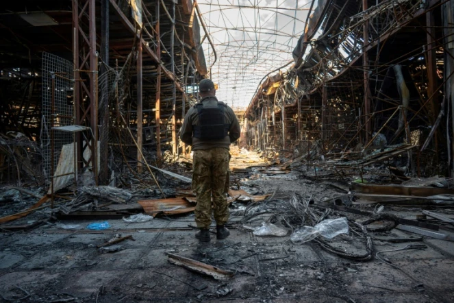 Un policier ukrainien recueille des éléments sur la destruction d'un des plus grands marchés européens de vêtements, "Barabashovo", à Kharkiv (est de l'Ukraine) le 16 mai 2022
