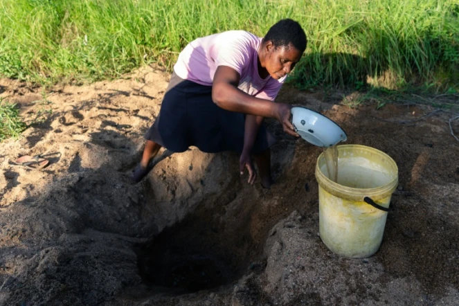Celia Munhangu creuse le sable pour trouver de l'eau, le 29 janvier 2020 à Buhera, au Zimbabwe