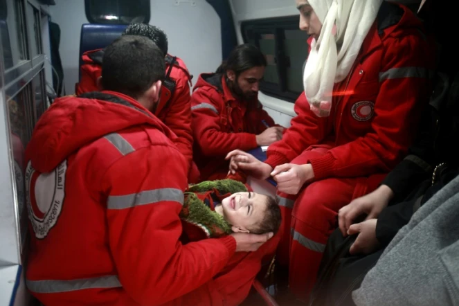 Du personnel du Croissant Rouge syrien évacue un enfant de Douma, dans la Ghouta orientale assiégée par le régime de Damas, le 26 décembre 2017  