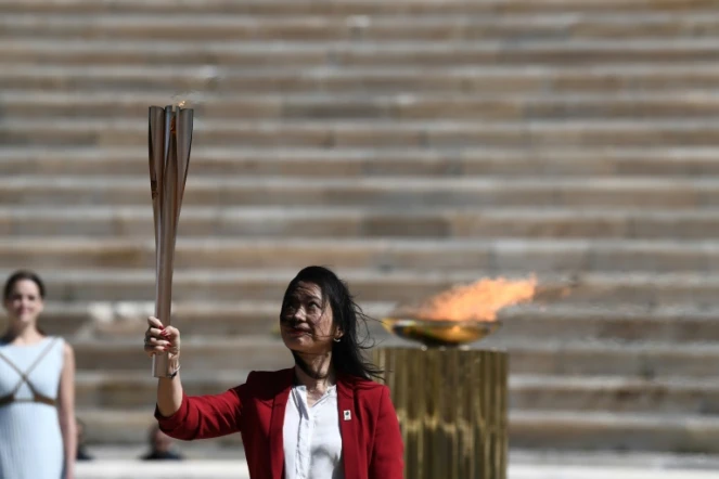 L'ex-championne japonaise de natation Imoto Naoko brandit la flamme olympique qu'elle vient de recevoir des autorités grecques à Athènes, le 19 mars 2020 