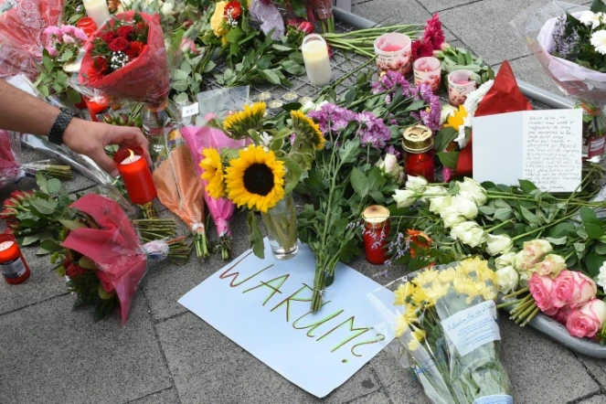 Bougies, fleurs et note où est inscrit "Pourquoi" rendent hommage aux neuf victimes du forcené, à l'entrée du centre commercial de Munich le 23 juillet 2016