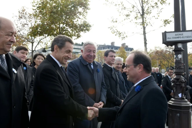 Poignée de mains entre François Hollande (D) et Nicolas Sarkozy, en présence de Jean-Yves Le Drian, Gérard Larcher, Manuel Valls et Claude Bartolone lors de la commémoration de l'amistrice, le 11 novembre 2015 sur les Champs Elysées à Paris