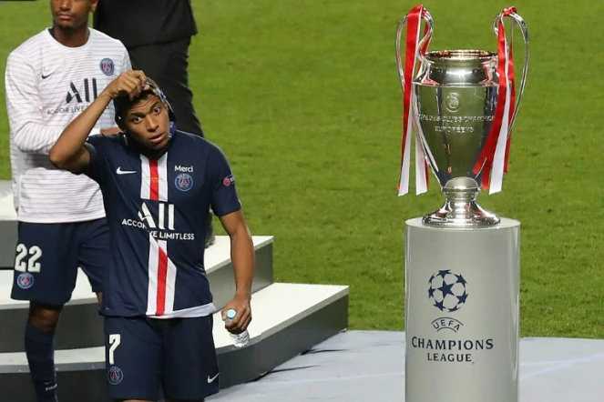 L'attaquant du Paris Saint-Germain Kylian Mbappé enlève sa médaille de finaliste en passant à côté du trophée de vainqueur de la Ligue des champions après la défaite en finale contre le Bayern Munich le 23 août 2020 à Lisbonne