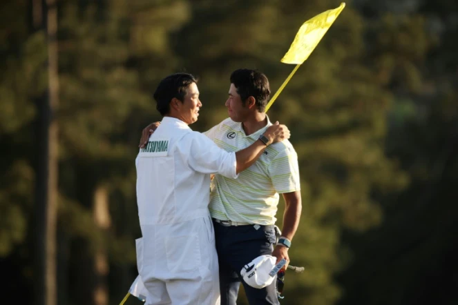 photo d'archives prise le 10 avril 2021 montrant le golfeur japonais Hideki Matsuyama, avec son caddie Shota Hayafuji, sur le green du 18ème trou après avoir remporté le Masters à Augusta, Géorgie, le 11 avril 2021
