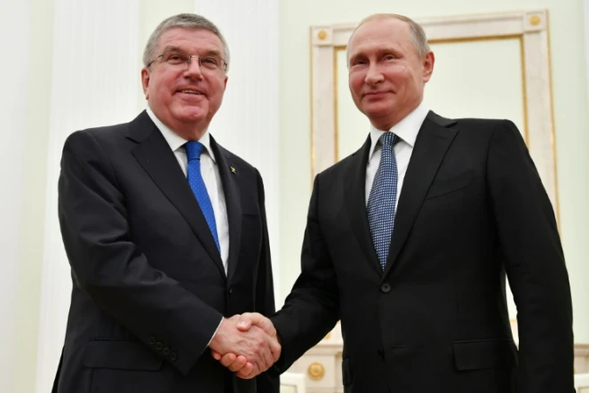 Le président russe Vladimir Poutine (d.) serre la main du président du Comité international olympique (CIO) Thomas Bach lors de leur rencontre au Kremlin à Moscou, le 15 juillet 2018