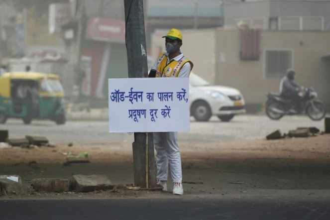 Un volontaire de la défense civile affiche un avertissement aux conducteurs après l'imposition de la circulation alternée en plein pic de pollution à New Delhi, le 4 novembre 2019
