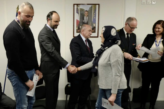Edouard Philippe et le ministre de l'Intérieur Gérard Collomb (C) serrent la main de réfugiés à Lyon, le 19 février 2018
