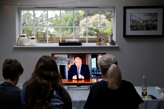 Une famille regarde une allocution télévisée du premier ministre britannique, Boris Johnson, à Hartley Wintney, à l'ouest de Londres, le 10 mai 2020