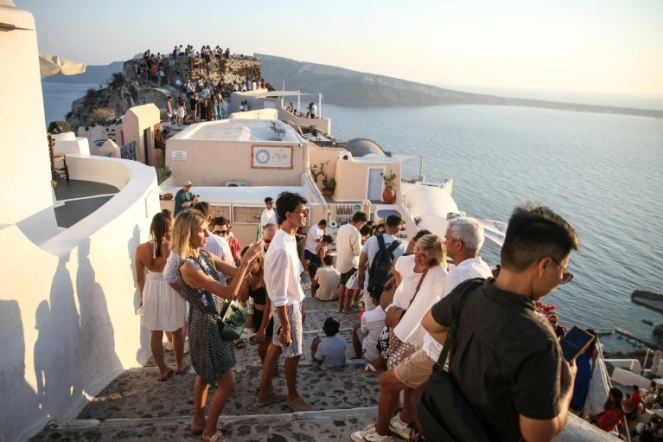 Des touristes attendent le coucher du soleil dans le village d'Oia sur l'île grecque de Santorin, le 20 juillet 2024