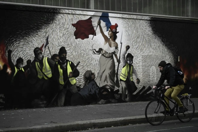 Un cycliste passe devant une fresque de l'artiste PBOY à Paris, mettant en scène des "gilets jaunes" et inspirée par le tableau "La Liberté guidant le Peuple" d'Eugène Delacroix, le 8 janvier 2019