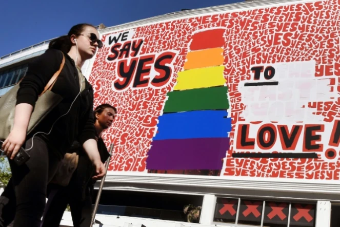 Des personnes passent devant un immense panneau d'affichage pour le "oui" au mariage gay à Sydney le 14 bovembre 2017