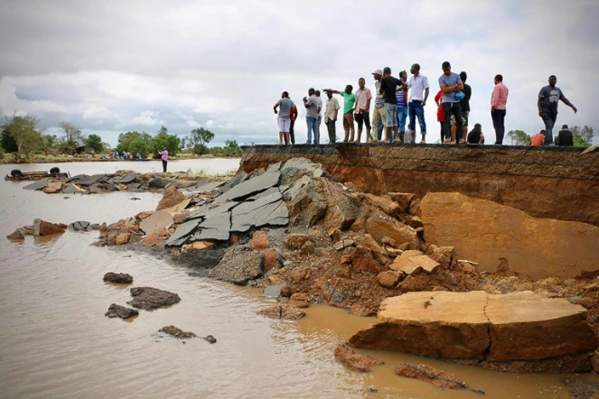 Des habitants debout près d'une route endommagée entre Beira et Chimoio, dans le centre du Mozambique, le 19 mars 2019, après le passage du cyclone Idai