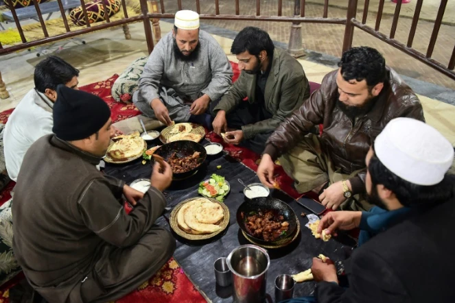 Des Pakistanais dégustent de la viande grillée au restaurant Tikka Nisar Charsi (Tikka "fumeur de haschich" en référence aux habitudes assumées du patron), à Namak Mandi, le coeur gastronomique de Peshawar, le 6 décembre 2018