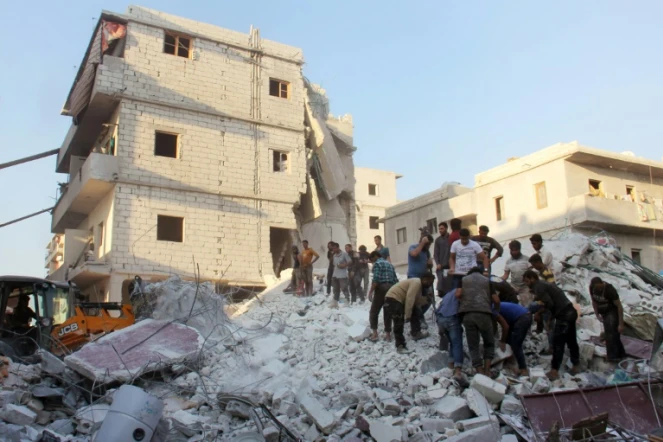 Des habitants et des casques blancs cherchent des survivants le 29 septembre 2017 sous les décombres d'un bâtiment détruit par une frappe aérienne à Harim (nord-ouest) dans la province d'Idlib 