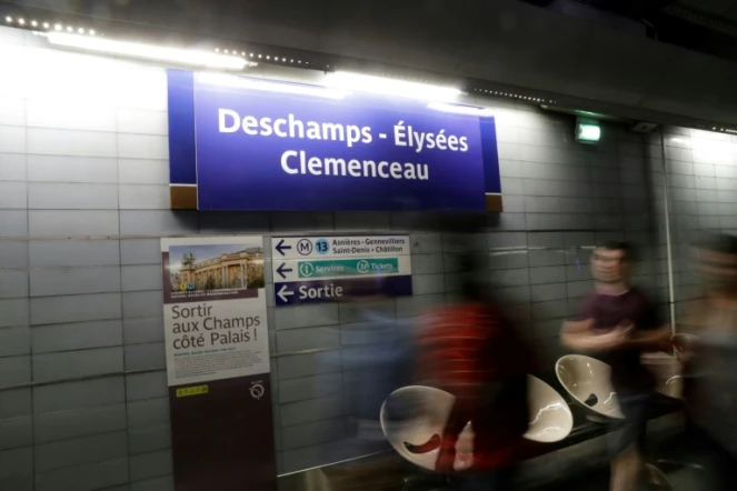 Des passagers du métro de Paris marchent devant l'affiche "Deschamps - Elysées Clemenceau", référence au nom de l'entraîneur de l'équipe de France de football Didier Deschamps, à la station de Champs - Elysées Clemenceau le 16 juillet 2018