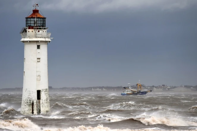 Un bateau de pêche passe le 9 février 2020 devant le phare de New Brighton, dans le nord-ouest de l'Angleterre, où la tempête Ciara est arrivée