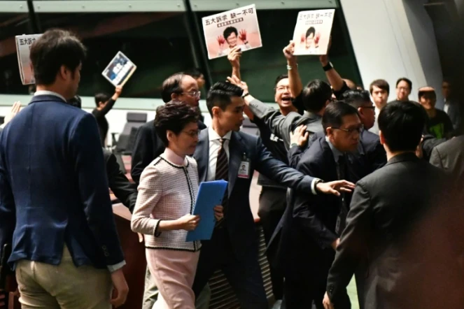 La cheffe de l'exécutif hongkongais Carrie Lam (c) quitte le Parlement local après avoir été chahutée par des parlementaires, le 16 octobre 2019