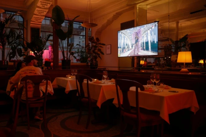 La cérémonie d'ouverture des Jeux olympiques de Paris 2024 passe sur un écran de télévision dans un restaurant à Paris, le 26 juillet 2024