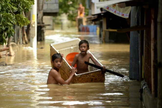 Des enfants dans une rue inondée le 18 décembre 2015 à Candaba aux Philippines