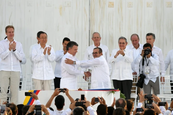 Le président colombien Juan Manuel Santos (G au centre serre la main du chef des Farc, Timoleon Jimenez, alias Timochenko (D au centre) scellant l'accord de paix historique
