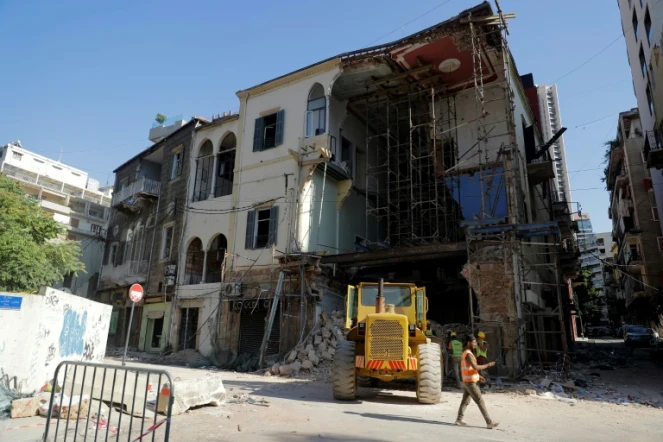 Des ouvriers enlèvent les décombres sous un bâtiment partiellement détruit par l'explosion dans le port de Beyrouth, le 26 août 2020 au Liban